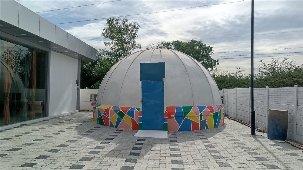 A finished dome theatre with a colourful mosaic base on a campus